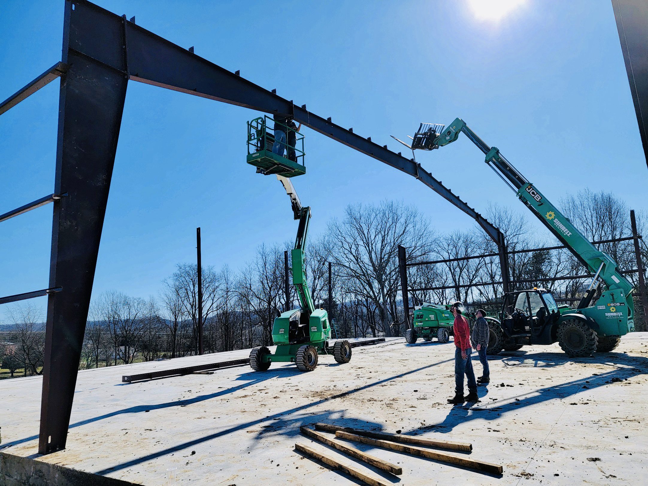 A man standing next to a crane on top of a pile of wood.
