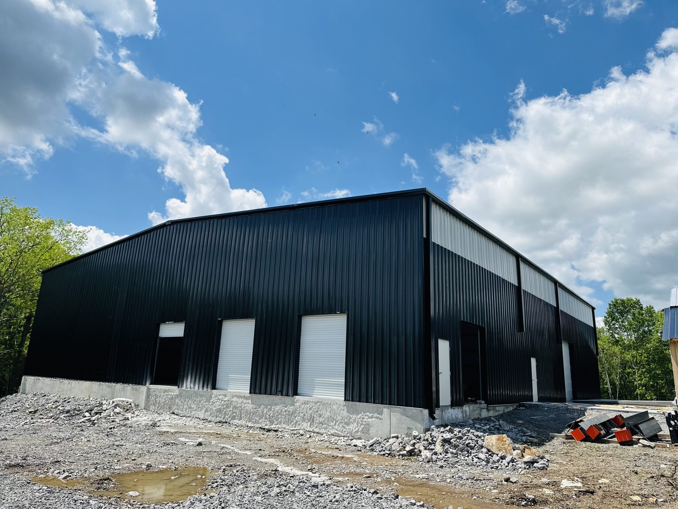 A large black building sitting on top of a gravel field.