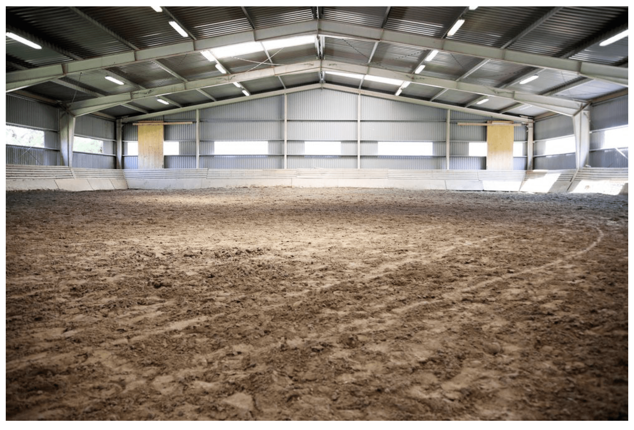 A large indoor arena with dirt and sand.