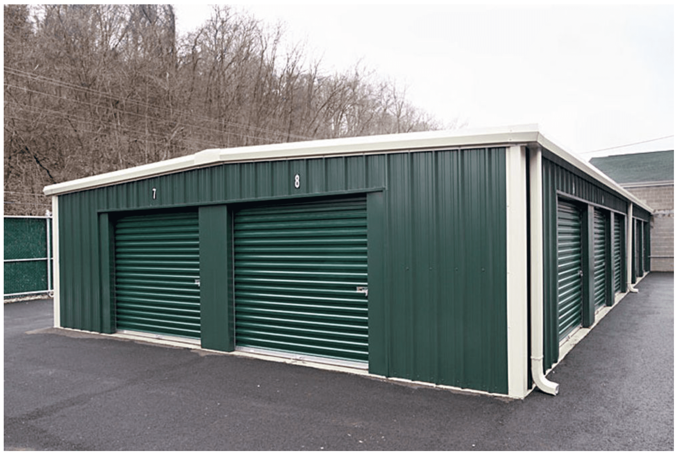 A green and white storage building with two doors.