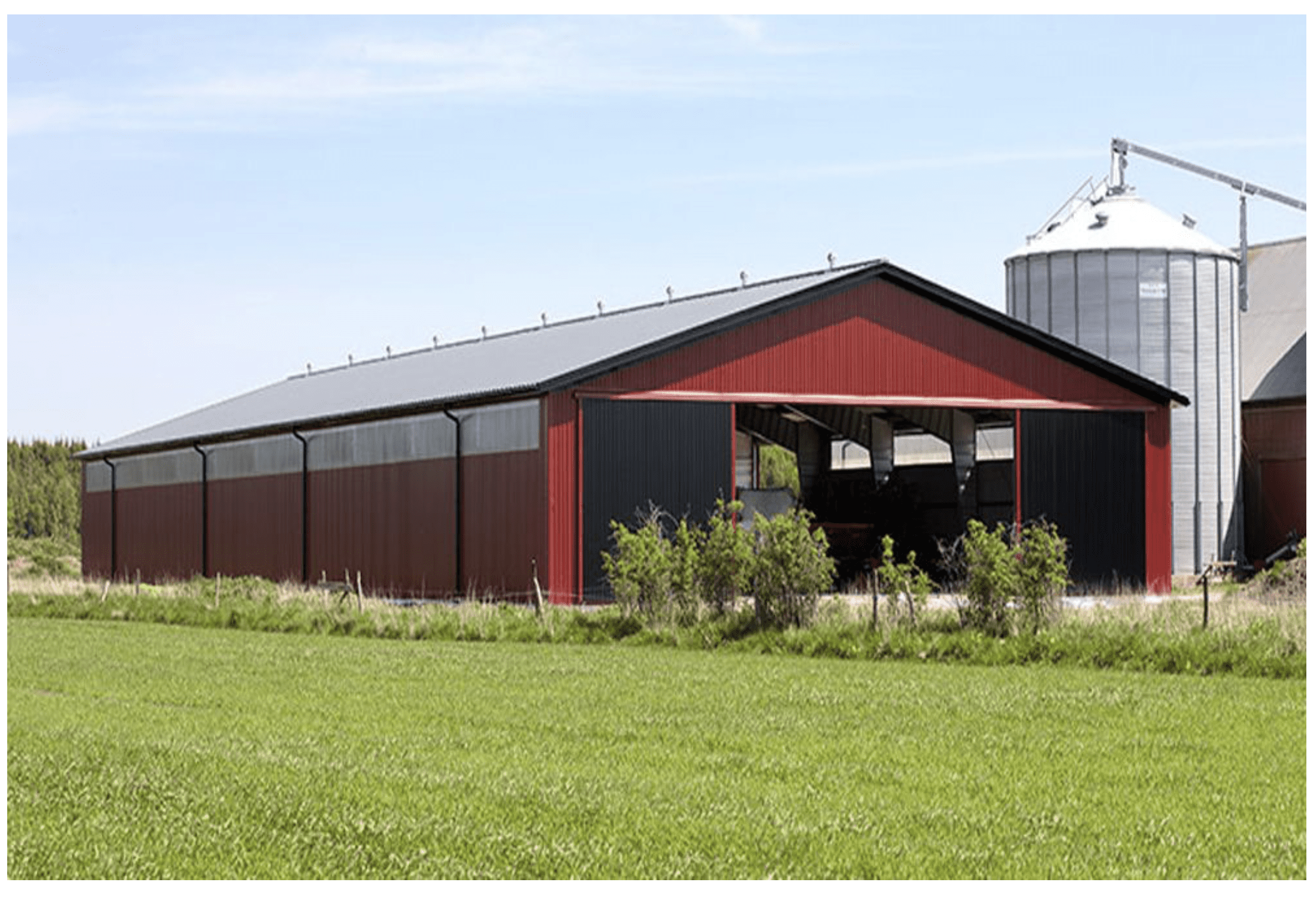 A barn with a silo in the background.